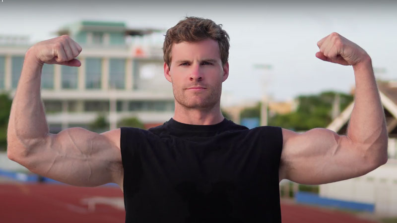 A photo of the coach standing outside flexing his biceps.